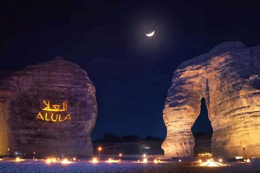 Illuminated rock formations with the text 'ALULA' and a crescent moon in the sky. 3