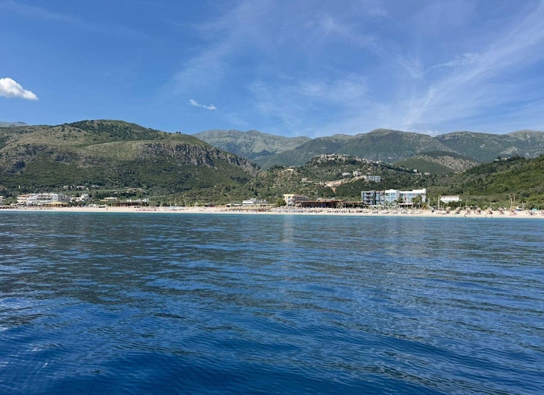 A coastal landscape with a beach, buildings, and mountains in the background. 5