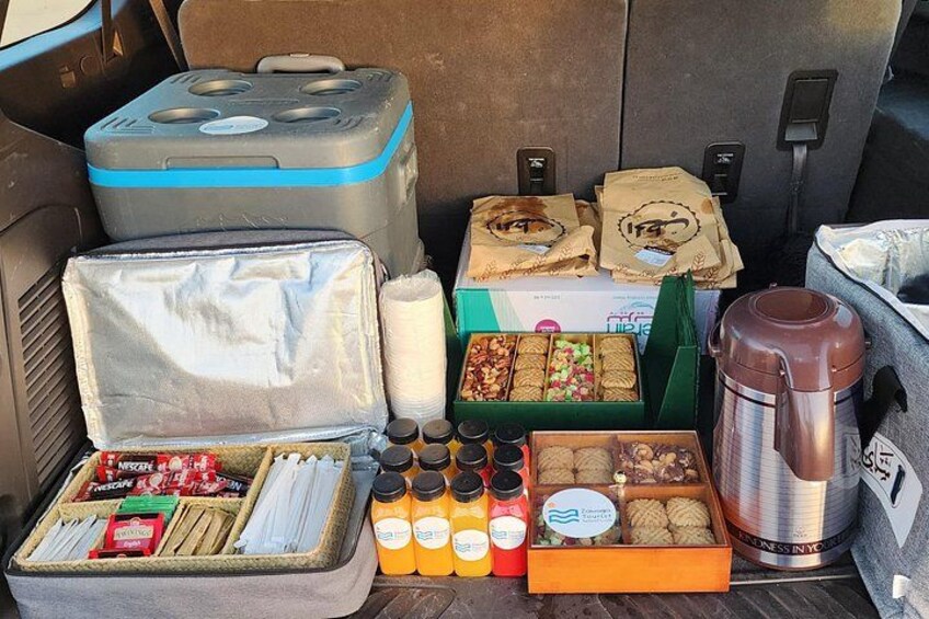 A car trunk filled with various items including a cooler, food, and beverages. 4