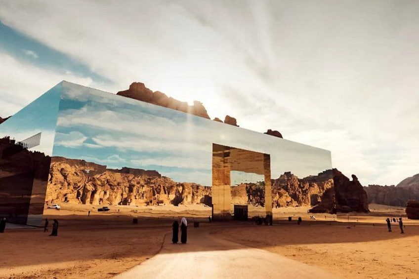 A modern building with a reflective glass facade, set against a desert landscape with rocky formations and a clear sky. 4