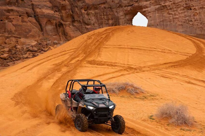A quad bike on a sandy trail with a rocky cliff in the background. 5
