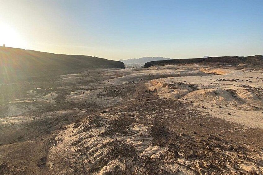 A barren landscape with undulating terrain and distant mountains. 3