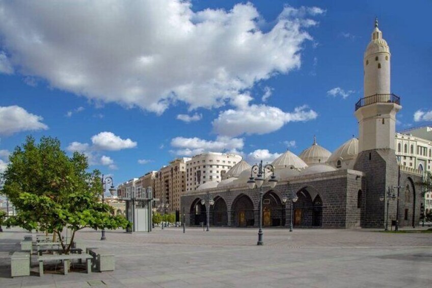 A mosque with a tall minaret, arched entrance, and domes, surrounded by a plaza with benches and trees. 5