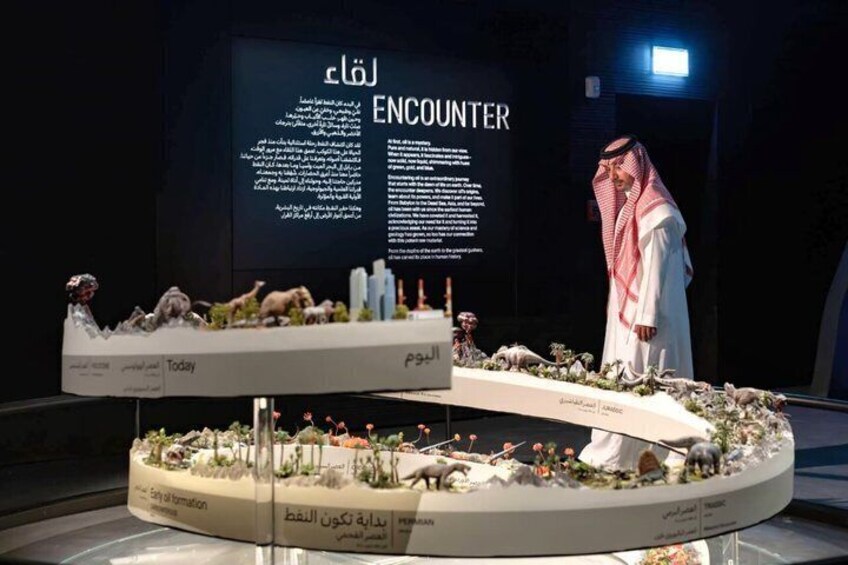 A model display with animals and text in Arabic, a person in traditional attire, and a dark background with a light source. 5