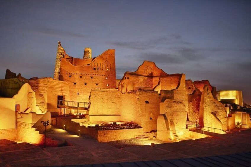 A well-lit historical site with ancient stone buildings and a castle-like structure. 1