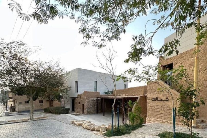 A courtyard with a modern building, traditional brick structures, and a tree. 2