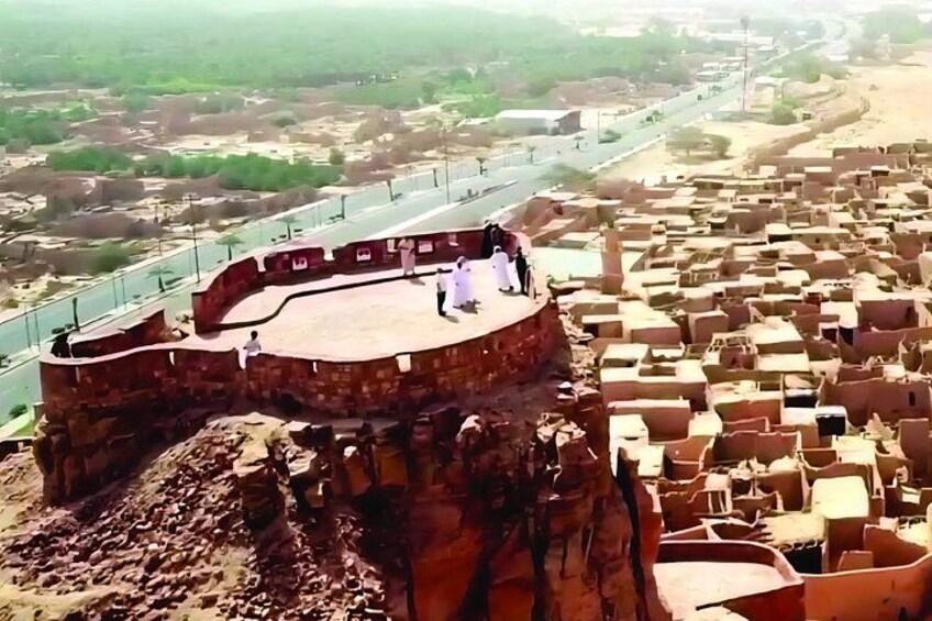 A historical fort with a stage, surrounded by traditional buildings and a river. 2