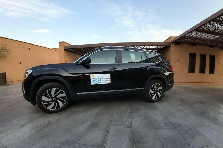 A black SUV parked on a paved surface with a building in the background. 1