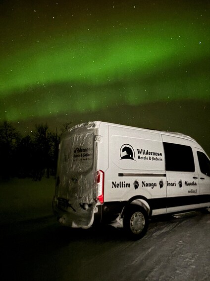 A white van with 'Wilderness Hotels & Safaris' branding parked on a road at night. 5