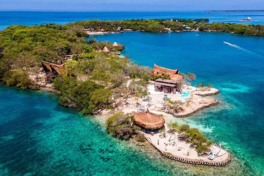 An aerial view of a tropical island with clear turquoise waters, lush greenery, and traditional thatched-roof structures. 3