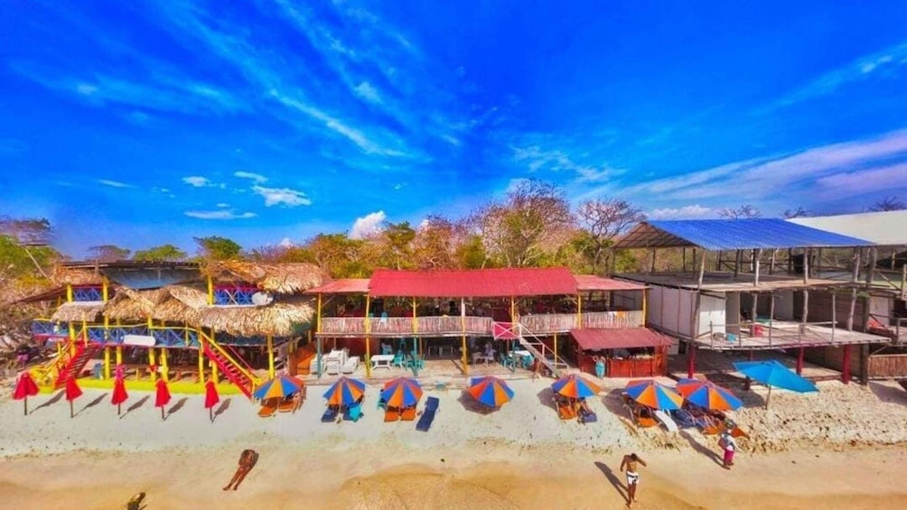 A beach with colorful umbrellas, a playground, and a building with a red roof. 5