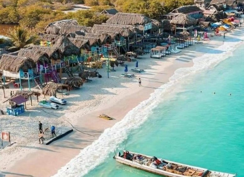 A beach with thatched-roof huts, a sandy shore, and a boat near the water. 1