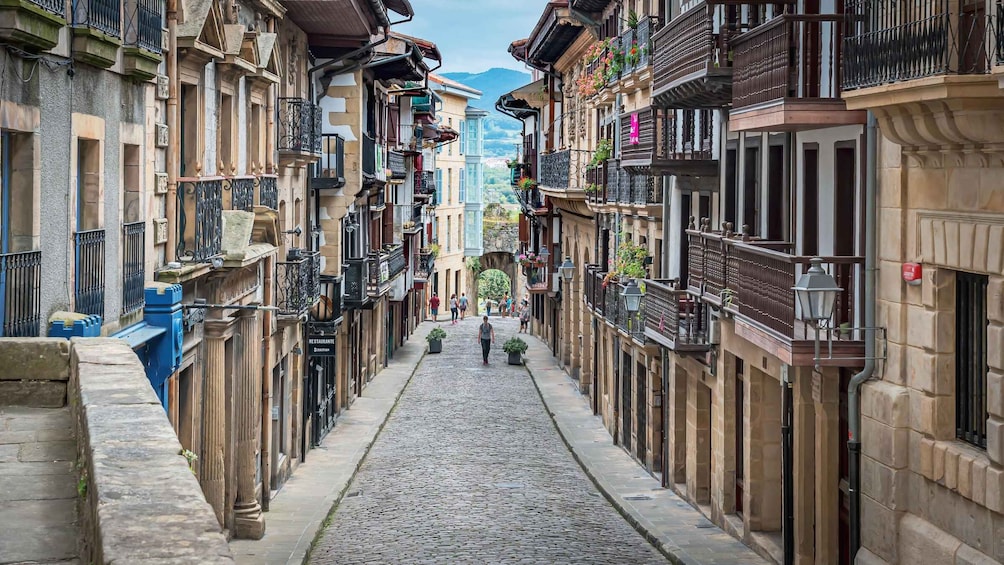 A cobblestone street flanked by historic buildings with balconies and flower boxes. 5