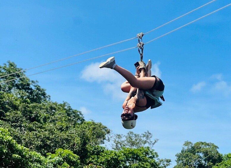 A person performing an aerial acrobatic stunt on a zip line. 3
