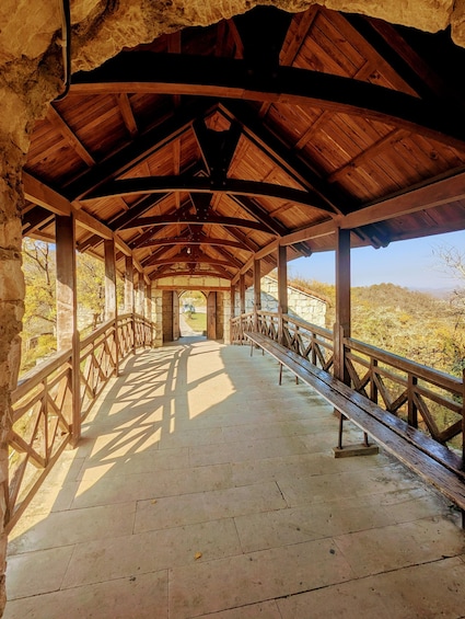 A covered wooden walkway with stone walls, leading to a scenic overlook. 3