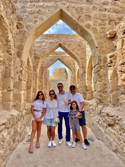 A family standing in an ancient stone archway with a clear sky in the background. 1