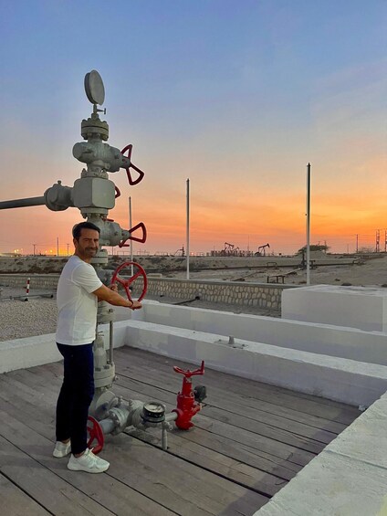 A person operating a valve on a rooftop with a sunset in the background. 2