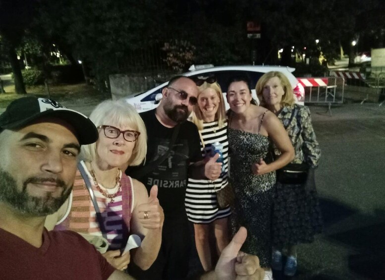 A group of people posing in front of a vehicle at night. 3