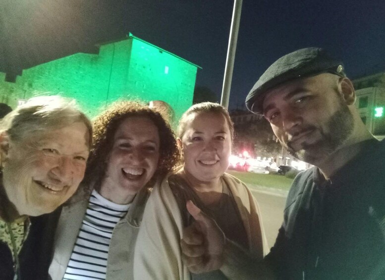 A group of people posing for a photo in an outdoor setting at night with a brightly lit building in the background. 2