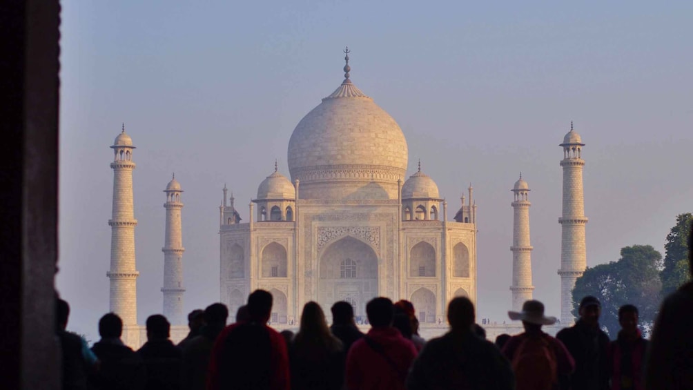 The Taj Mahal with four minarets and a crowd of people in the foreground. 2