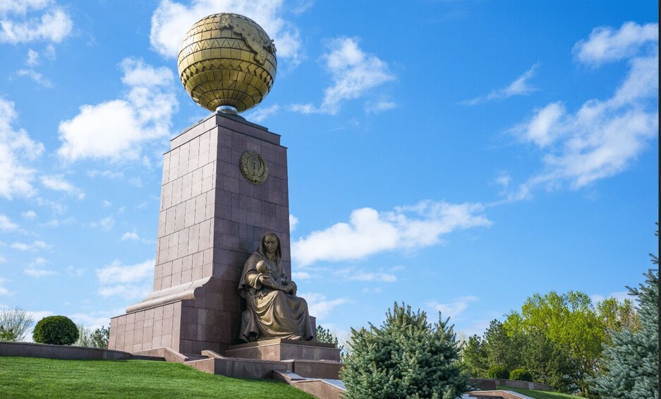 A monument with a globe on top and a statue of a woman holding a child. 2