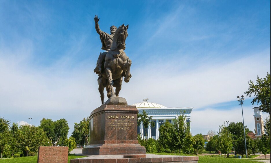 A statue of a man on horseback, a building with columns, and a clear blue sky. 3