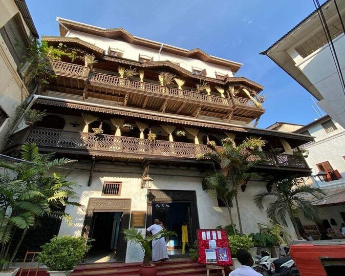 A multi-story building with ornate balconies and a red entrance. 4