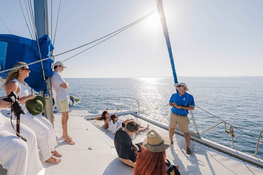 A sailboat with people on deck, a clear sky, and calm sea. 1