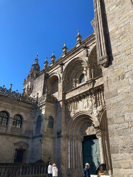 A historic building with ornate stonework, a green door, and a clear blue sky. 3