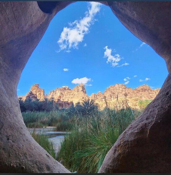 A natural rock arch framing a desert landscape with rocky formations and sparse vegetation. 2