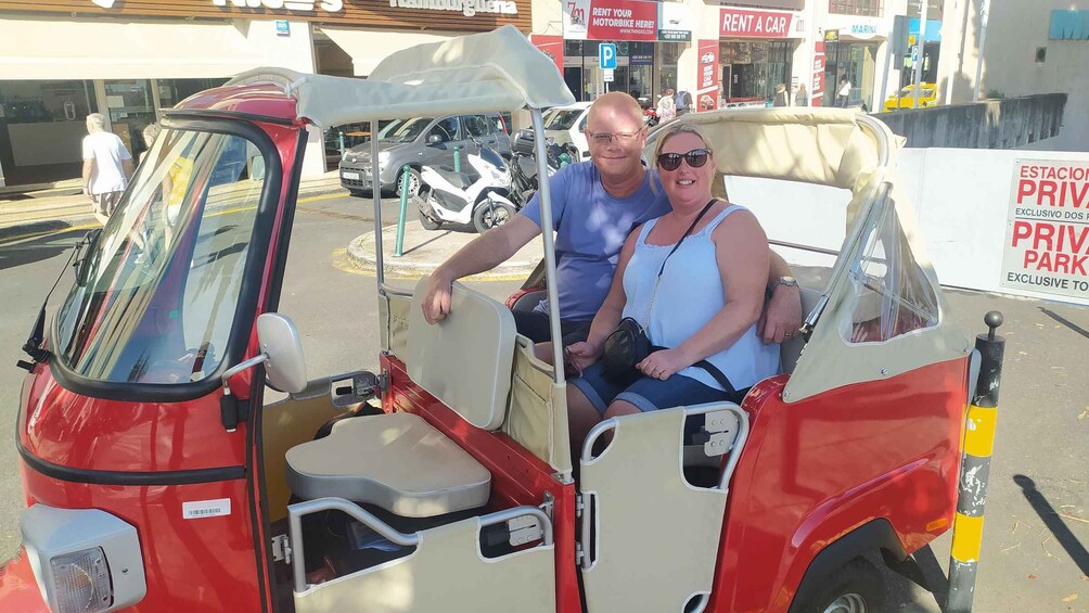 A red and white tuk-tuk parked in front of a building with signs for 'Rent a Car' and 'Private Parking'. 5