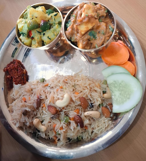 A plate with biryani, a vegetable curry, and a meat dish. 3