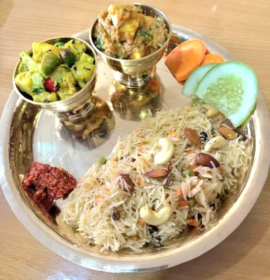 A plate of biryani with nuts, vegetables, and a side of curry. 2