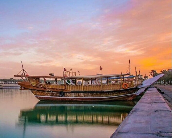 A traditional wooden boat docked at a pier during sunset. 2
