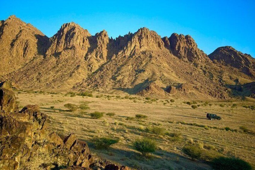 A desert landscape with rocky mountains and sparse vegetation. 3