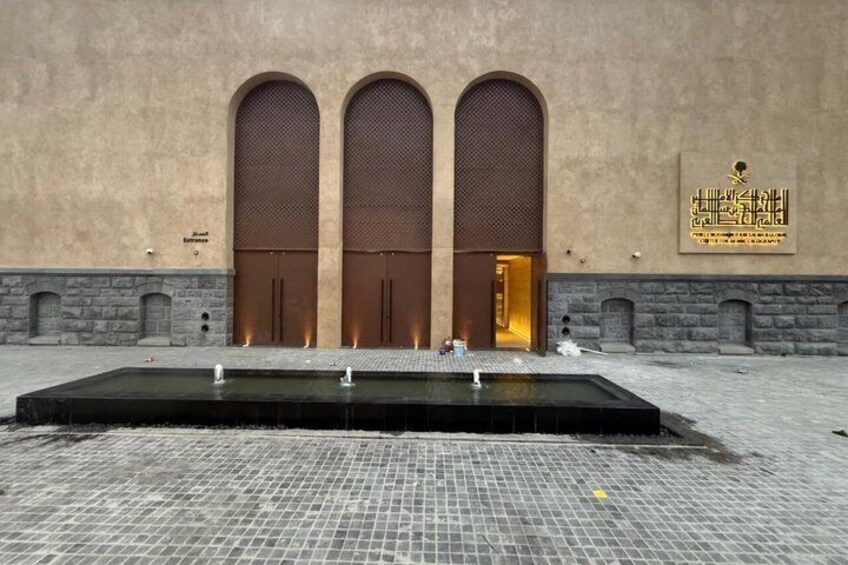 A building with three large arched doors and a water feature in front. 2