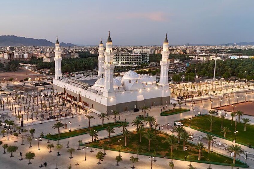 A large mosque with three minarets and a central dome, surrounded by a well-maintained courtyard with palm trees. 4