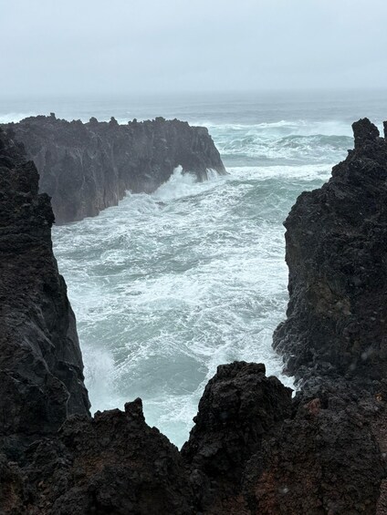 A rugged coastline with dark volcanic rock formations and turbulent ocean waves. 3