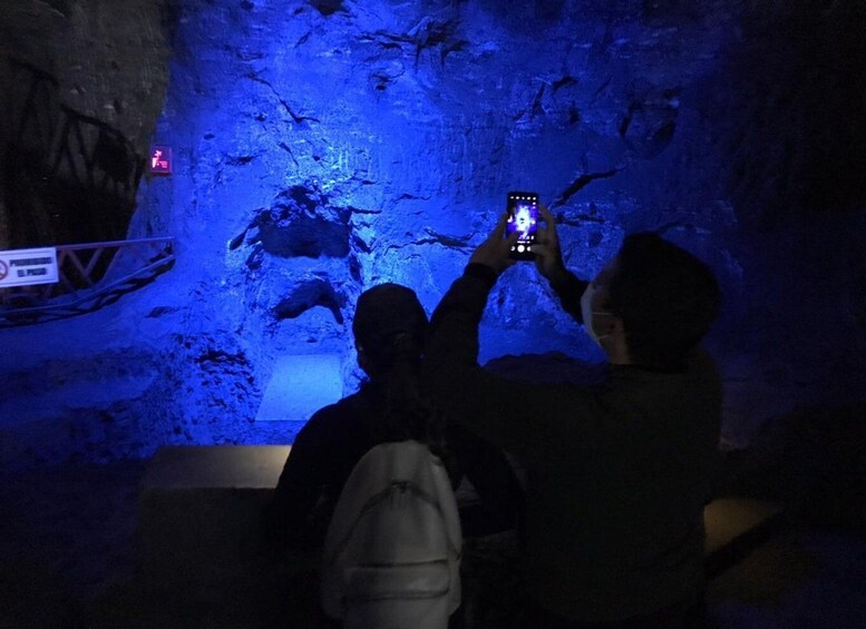 Two people taking a photo in a dimly lit cave with blue lighting. 2