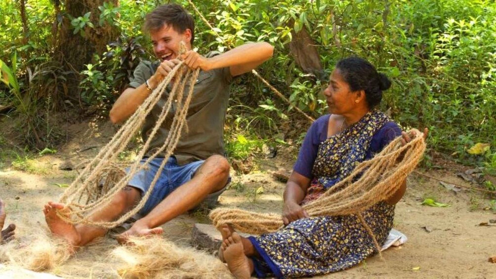 Two people sitting on the ground, weaving ropes. 2