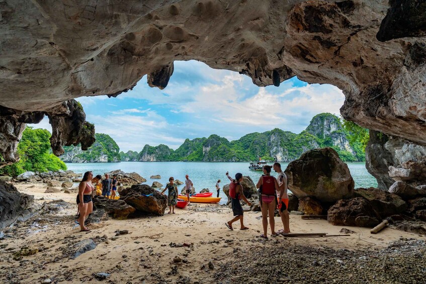A cave entrance with people and kayaks on a beach. 4