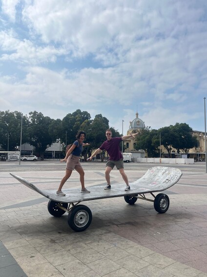 Two people pushing a cart on a paved area with a dome-shaped building in the background. 2