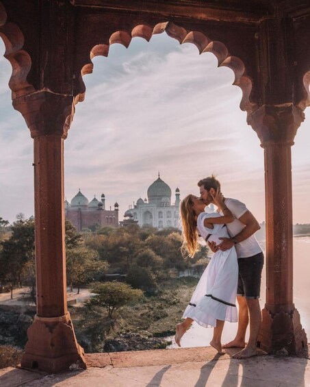 A couple kissing in an archway with the Taj Mahal in the background. 4