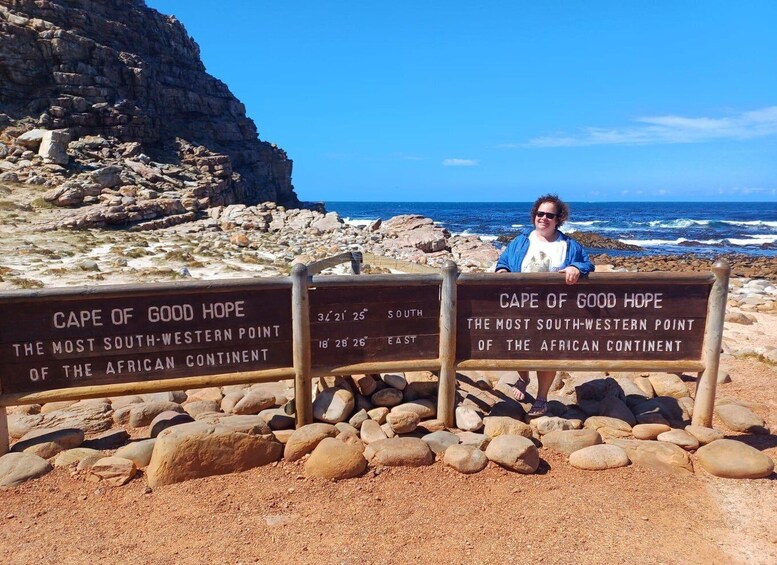 A person standing in front of a sign at Cape of Good Hope, the most southwestern point of the African continent. 1