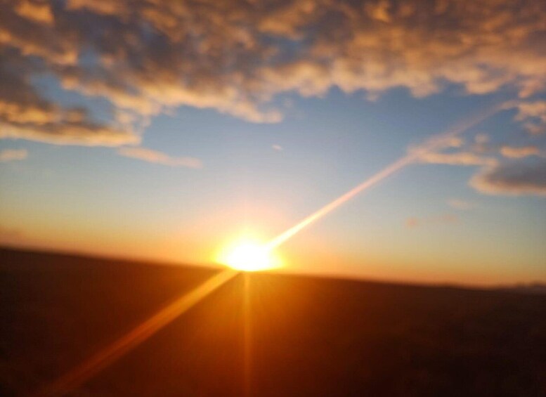 A sunset with the sun low on the horizon, casting a warm glow and creating a lens flare effect. 4