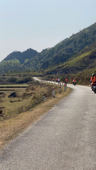 A gravel road with motorcyclists wearing orange vests. 1