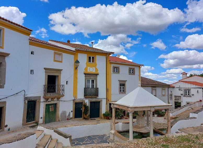 A white building with yellow trim and a red-tiled roof. 1
