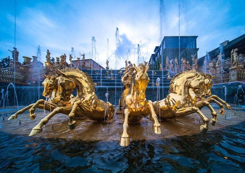 A golden horse fountain with water jets in a public square. 3