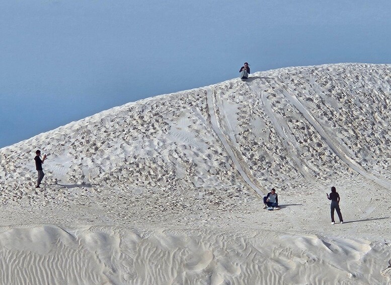 A snowy mountain with three people standing and one sitting. 2