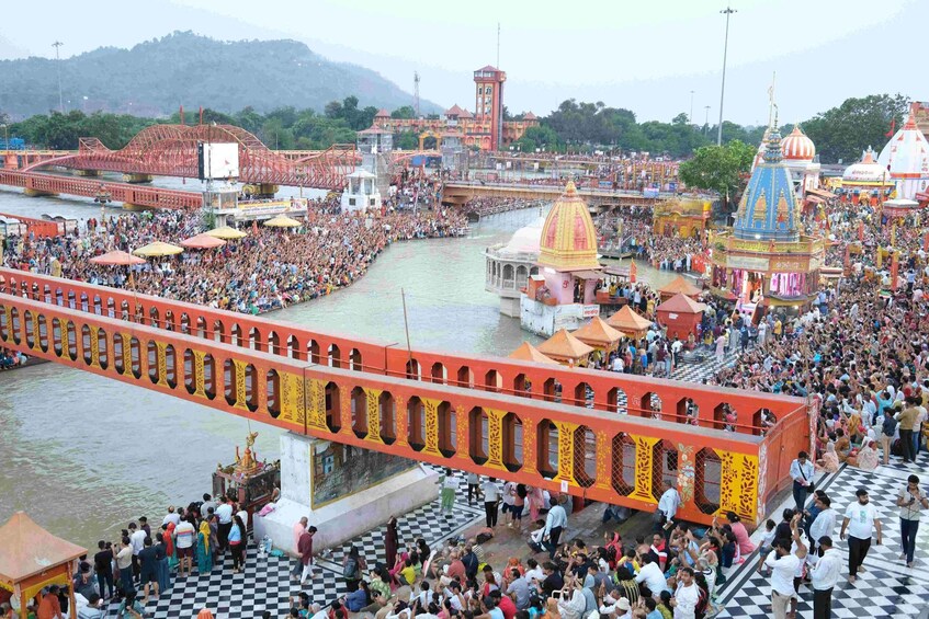 A crowded riverside festival with a large bridge, temples, and a checkered floor. 1